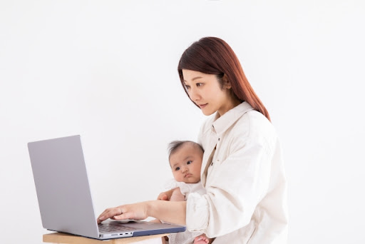 赤ちゃんを抱いてパソコンをする女性