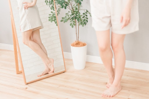 鏡の前で足を見る女性