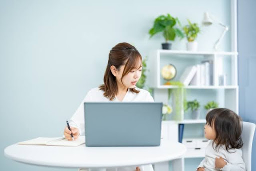 パソコンをしながら子供を見る女性